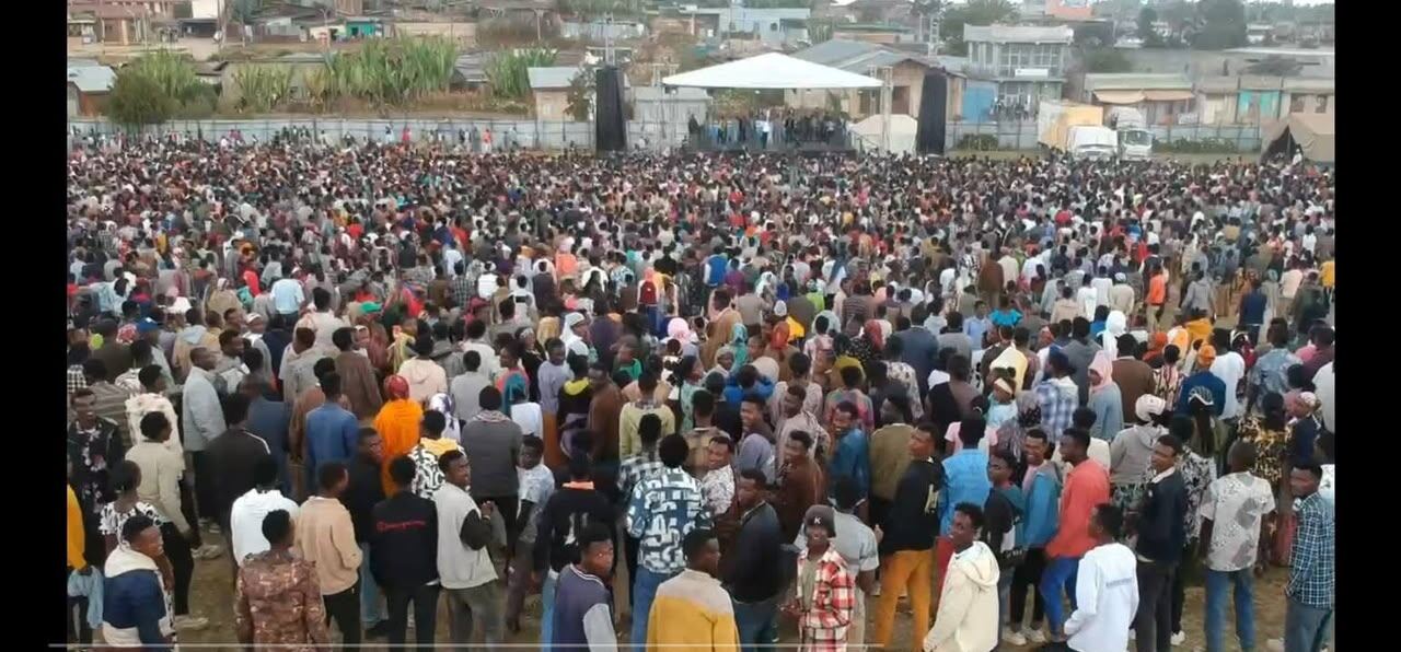 Aerial view of a crowd filling an open field at dusk