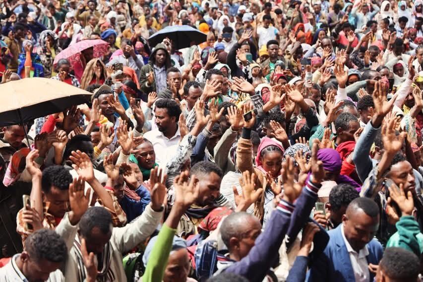 Hands raised in prayer across a dense crowd
