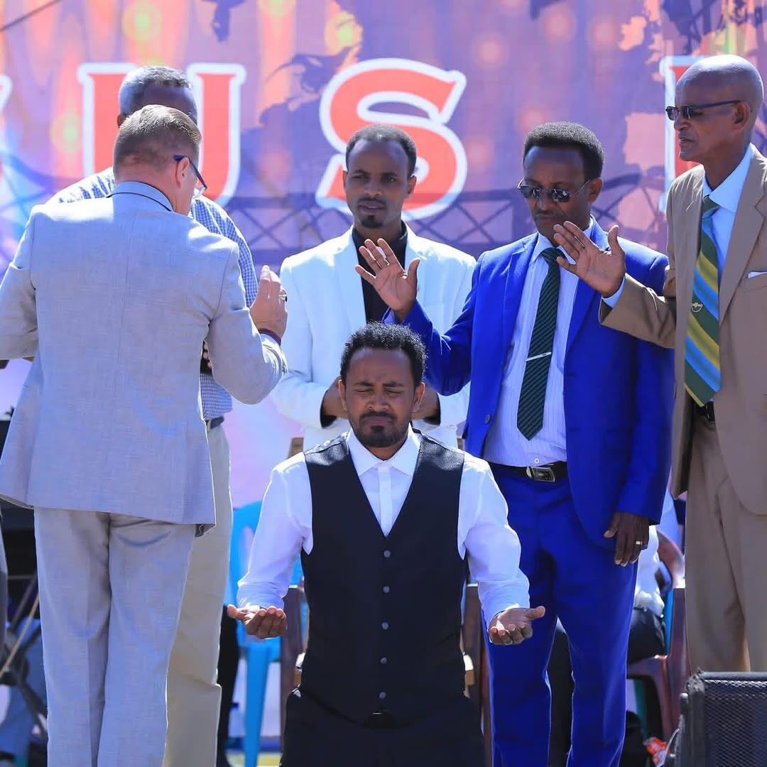 Ministers praying over a man kneeling on stage