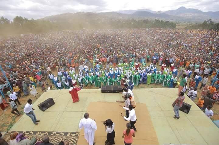 A robed choir singing in a cloud of dust before the crowd