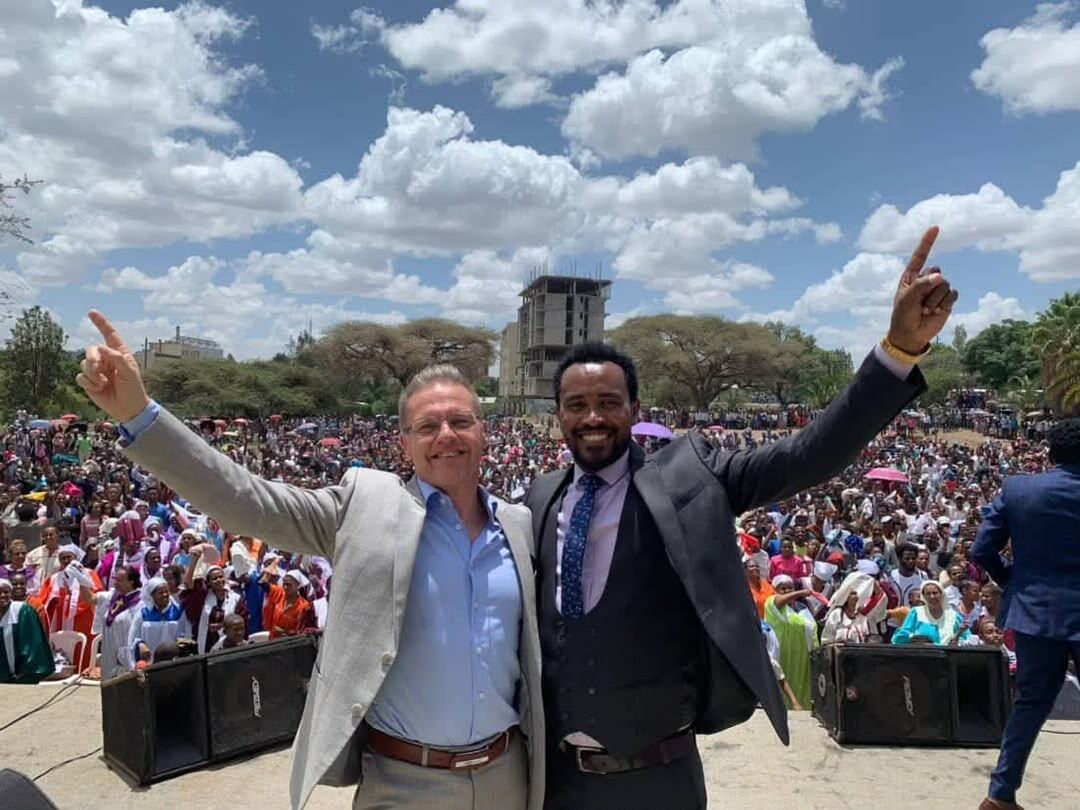 Evangelist Hailu Lemma with an international partner minister before a crowd