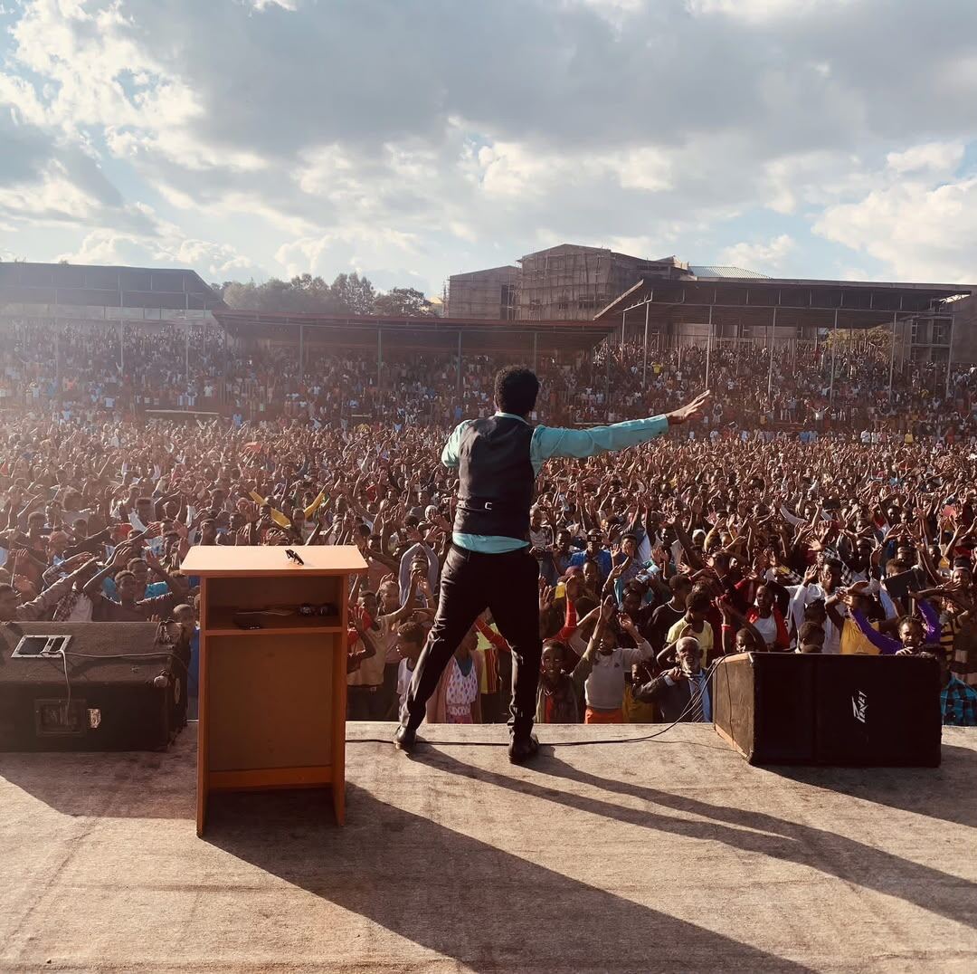 Evangelist Hailu Lemma addressing a packed stadium at golden hour